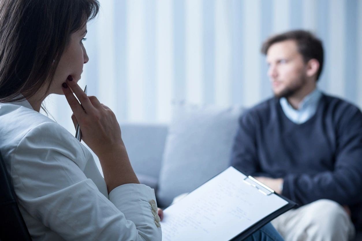 A woman sitting on the couch talking to a man.