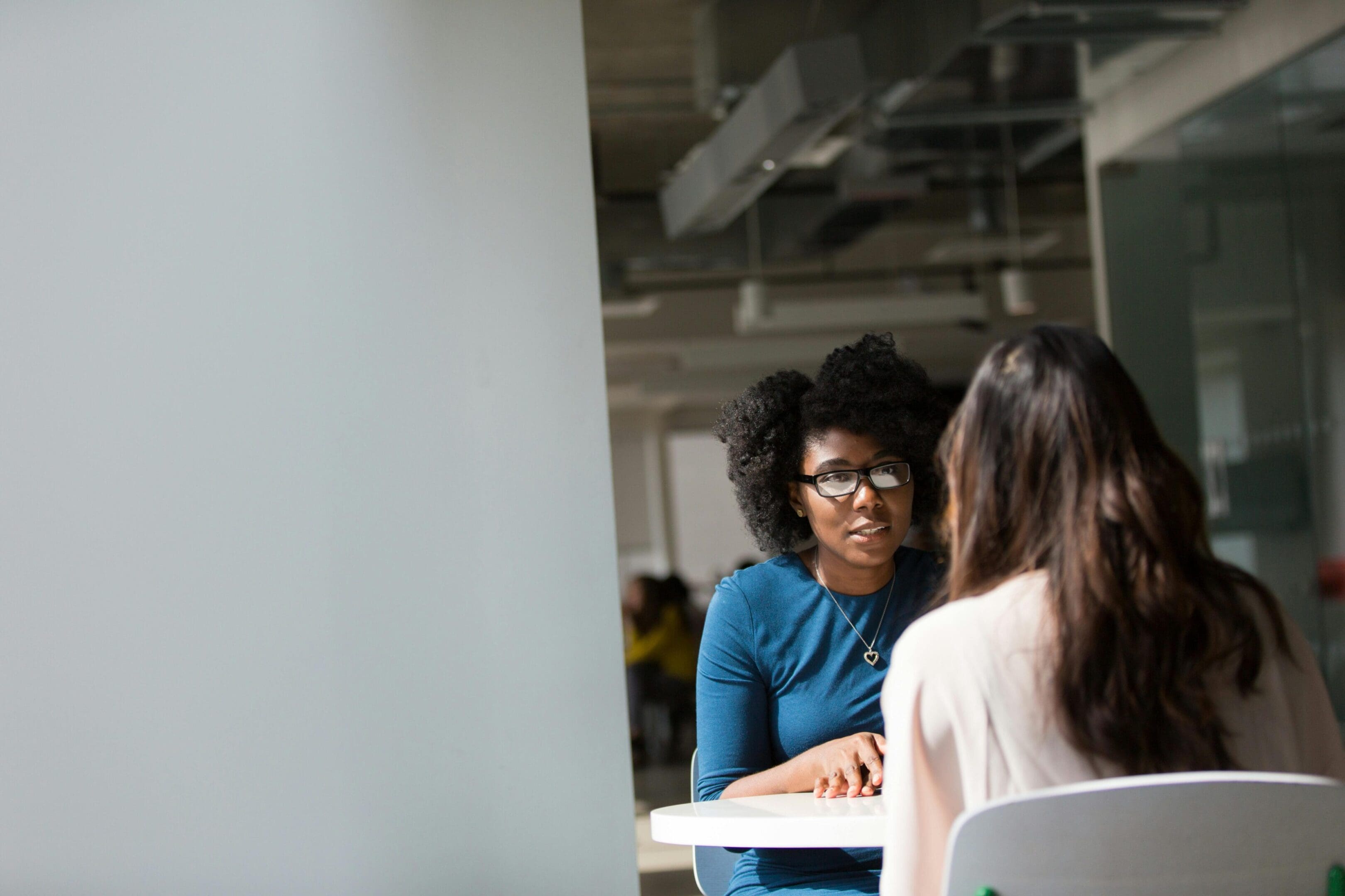 Two women are sitting at a table talking.