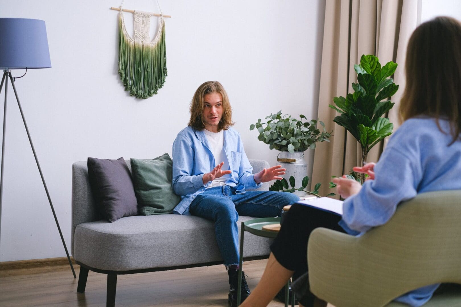 Two people sitting on a couch talking to each other.