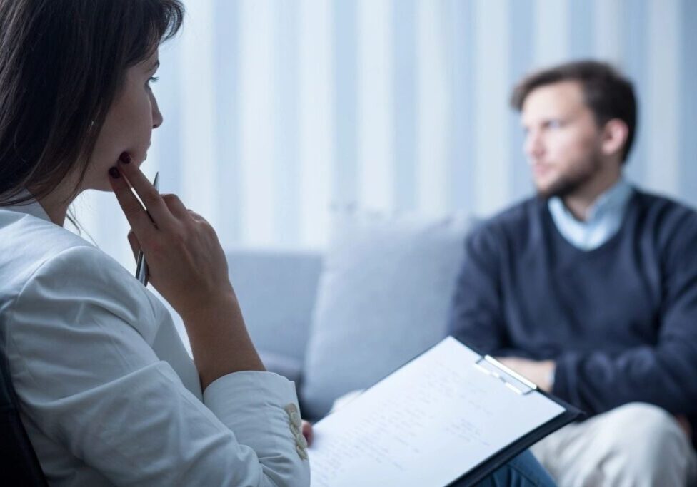 A woman sitting on the couch talking to a man.